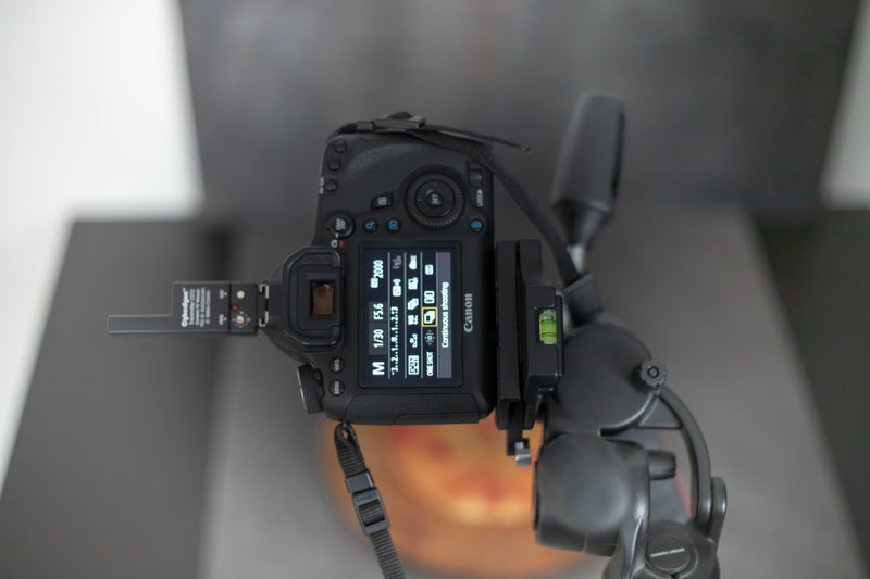 A Canon DSLR camera mounted on a tripod, displaying its rear screen with manual shooting settings — the kind of in-the-moment capture that becomes a Lightroom preset.