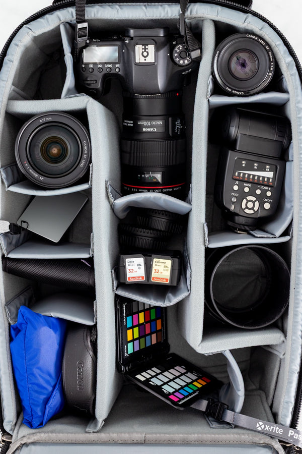 The Complete Library — a camera bag flat-lay showing all the photography gear, lenses, flash, color checker, and SD cards organized in dividers